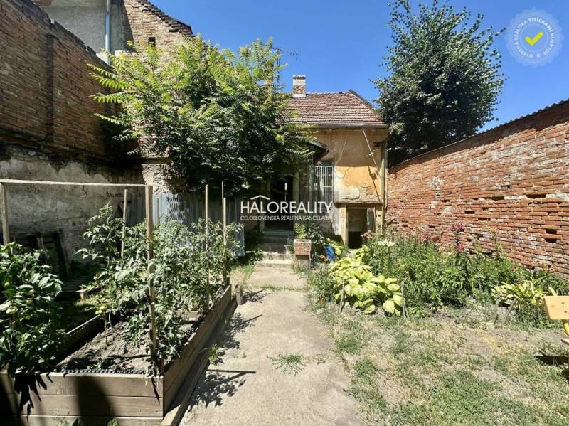 Der Hof eines Einfamilienhauses in Rimavská Sobota mit einem Garten und einer Ziegelmauer.