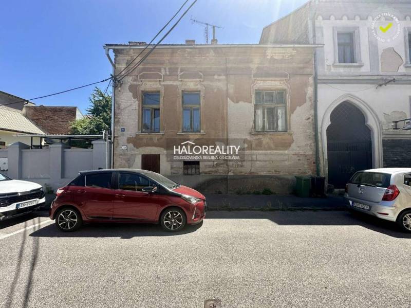 Eine Straße in Rimavská Sobota mit einem historischen Familienhaus und geparkten Autos.