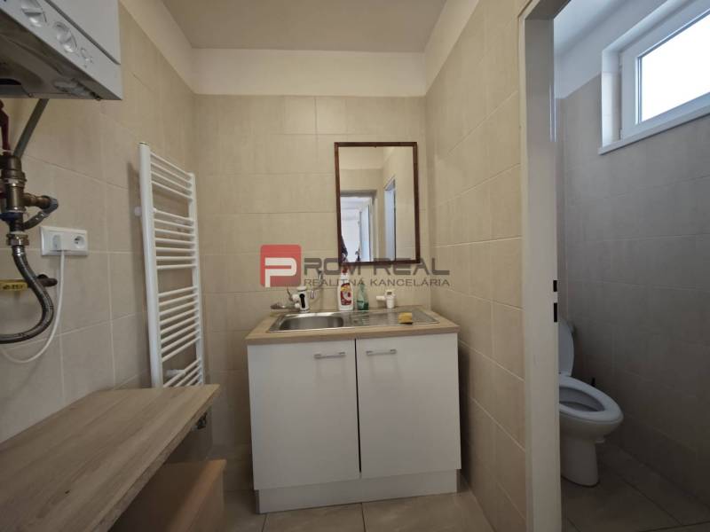Badezimmer mit Waschbecken und WC in der Šúrska-Straße, in der Nähe des Büros, helle Fliesen.