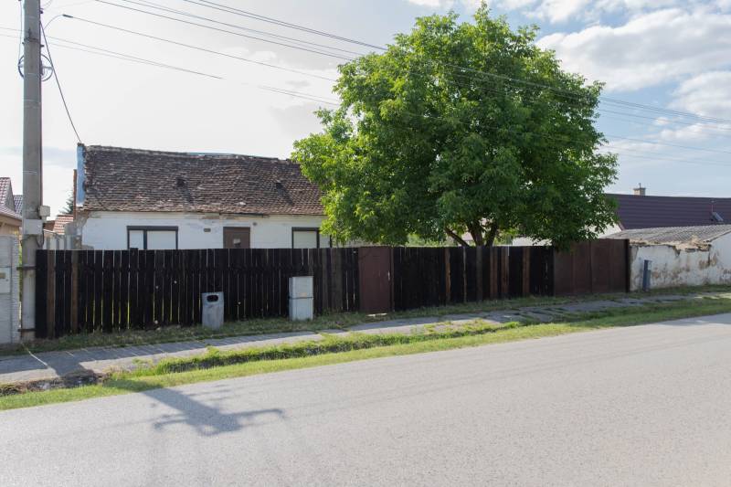 Ein Gebäude mit einem alten Dach in der Športová-Straße in Gajary, umgeben von einem Zaun. Grundstücke - Wohnen.
