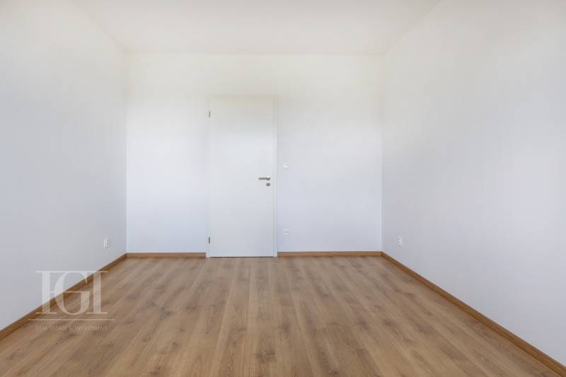 Ein leerer Raum mit Holzboden und weißen Wänden in einer 3-Zimmer-Wohnung.