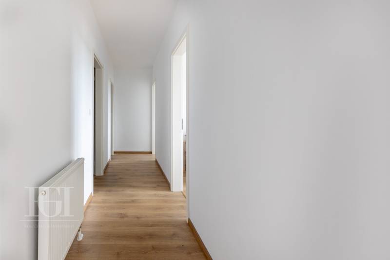 Der Flur in einer 3-Zimmer-Wohnung mit weißen Wänden und Holzboden.