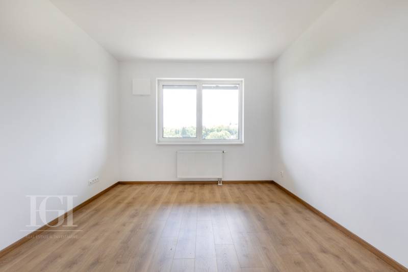 Ein leerer Raum mit Holzboden und einem großen Fenster in einer 3-Zimmer-Wohnung.