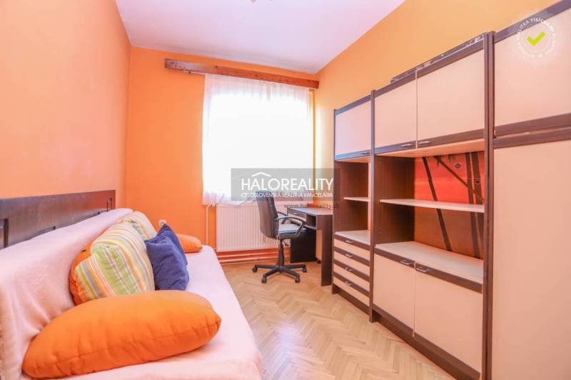 Ein Zimmer in einer 3-Zimmer-Wohnung mit orangefarbenen Wänden, einem Sofa, einem Tisch und Schränken.