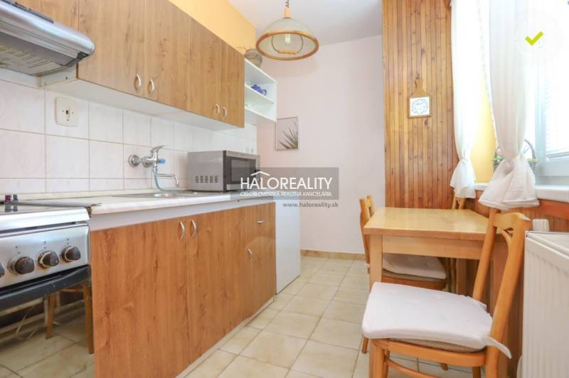Küche in einer 3-Zimmer-Wohnung mit Holzmöbeln, Herd und Mikrowelle.