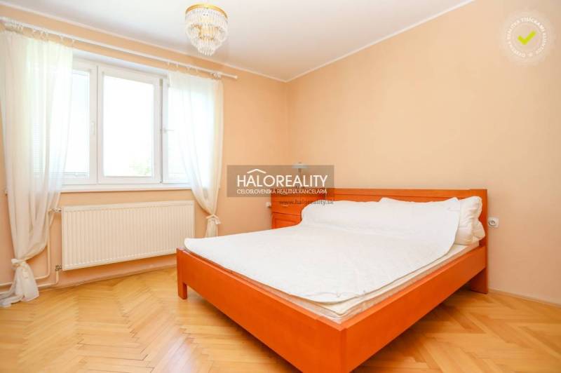 Helles Schlafzimmer in einer 3-Zimmer-Wohnung mit Bett, Holzboden und Vorhängen.
