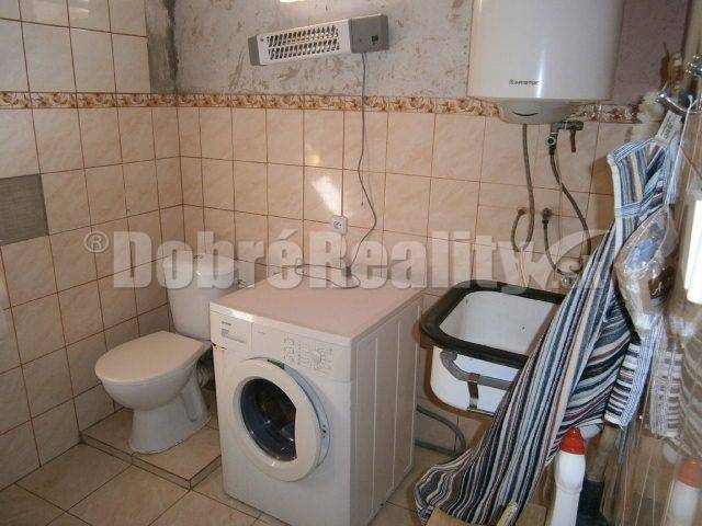 Badezimmer in einem Einfamilienhaus mit Waschmaschine, Toilette und Waschbecken.