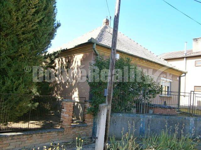 Ein Einfamilienhaus in Rúbaň mit einem älteren Äußeren, umgeben von einem Zaun und Vegetation.
