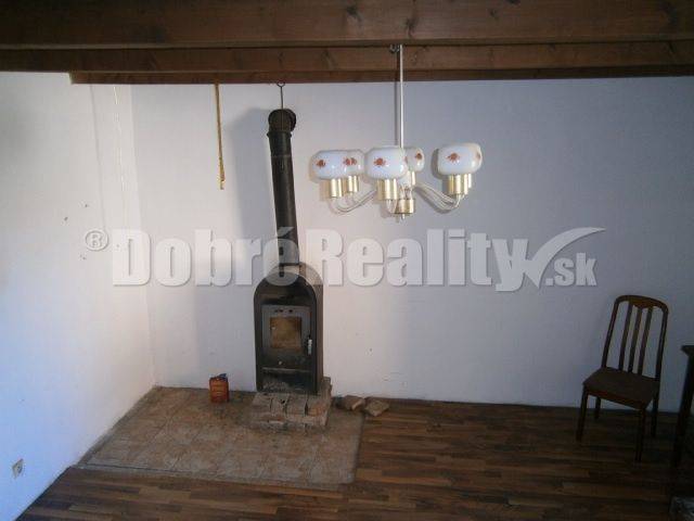 Innenraum eines Einfamilienhauses mit Ofen, Holzstuhl und Wandleuchte.