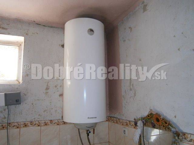 Ein elektrischer Boiler in einem Einfamilienhaus mit Wandverkleidung und kleinem Fenster.