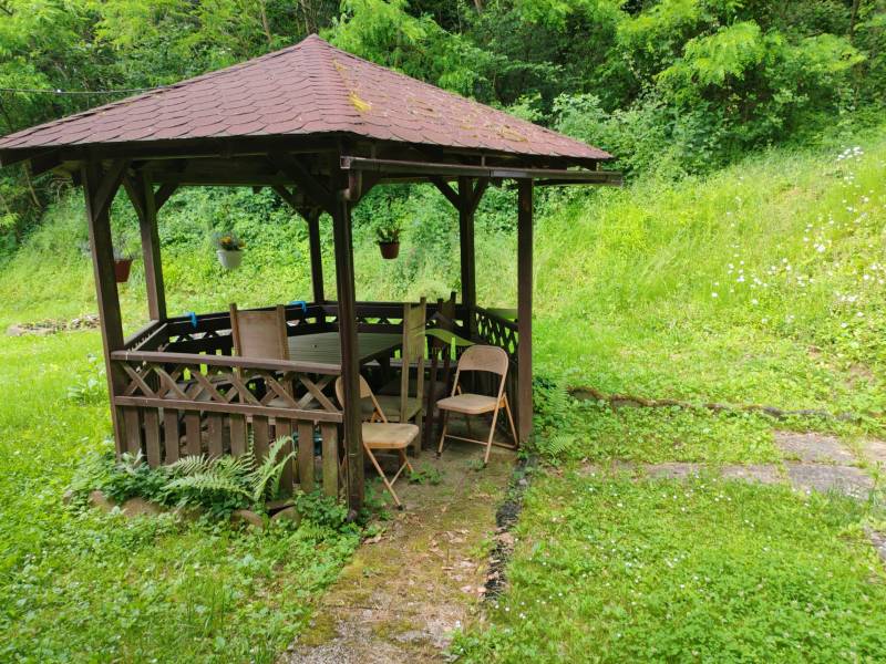 Ein hölzerner Pavillon mit Sitzgelegenheiten inmitten von Grünflächen bei der Hütte in der Straße Dobrá in Kvakovce.