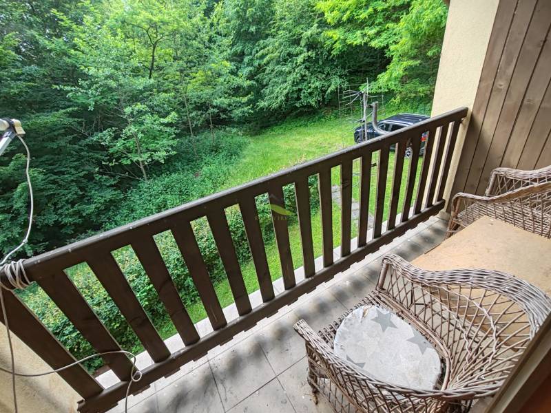 Der Balkon der Hütte mit Korbstühlen und Blick auf den Garten und das Grün.