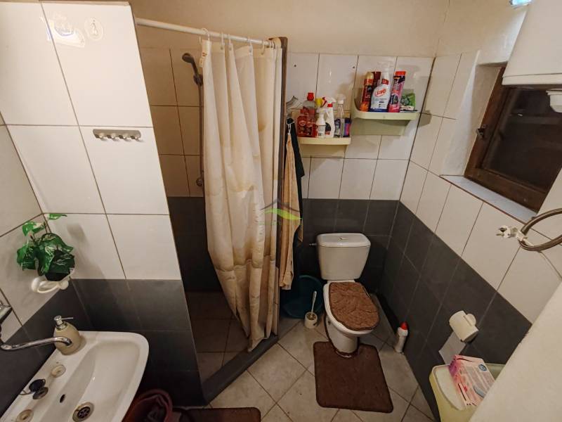 Badezimmer in der Hütte mit WC, Duschkabine und weißen Fliesen.