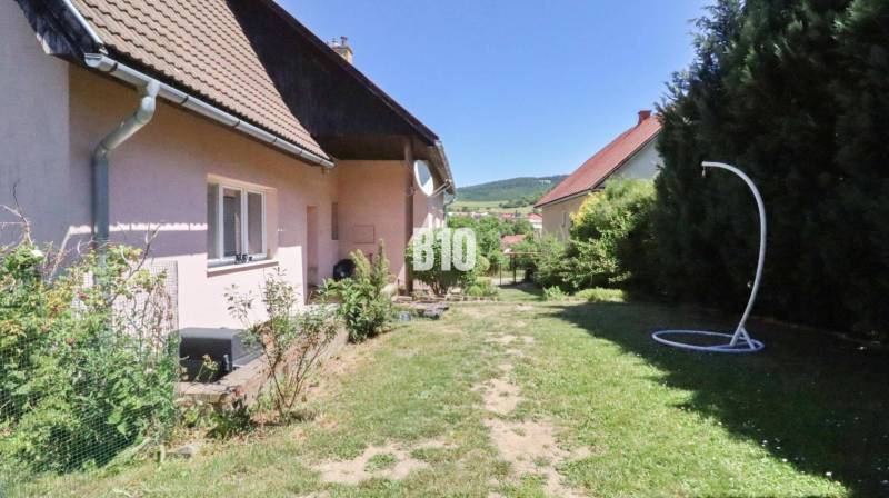 Garten beim Einfamilienhaus in der Stadt Podhradie mit Rasen und umliegender Natur.