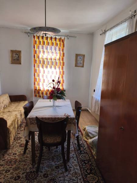 Esszimmer in einem Einfamilienhaus mit Tisch, Stühlen, Blumen, Teppich und Vorhang.