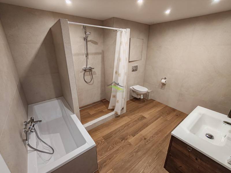 Badezimmer in einer 2-Zimmer-Wohnung mit Badewanne, Dusche, Waschbecken und Toilette.