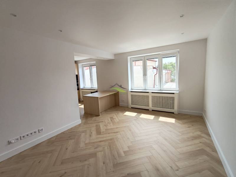 Helles Wohnzimmer in einer 2-Zimmer-Wohnung mit Holzboden und Fenstern.