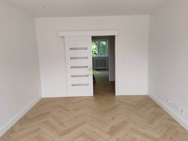 Ein Zimmer in einer 2-Zimmer-Wohnung mit Holzboden und weißen Schiebetüren.