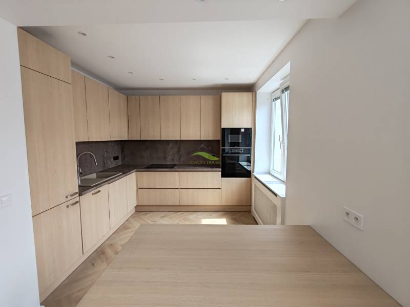 Küche in einer 2-Zimmer-Wohnung mit Holzschränken und eingebauten Geräten.
