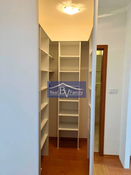 Ein Kleiderschrank in einer Einzimmerwohnung mit weißen Regalen und Holzboden.