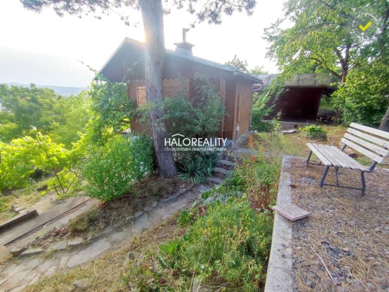 Gärten in Zvolen mit einer Hütte, einer Bank und reichlich Grün, die Entspannung in der Natur ermöglichen.