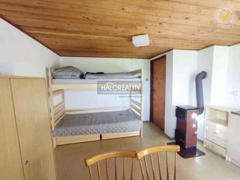 Ein Innenraum mit einem Etagenbett, einer Holzdecke, einem Schrank und einem Kachelofen in den Gärten.