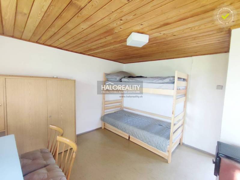 Einfaches Zimmer mit Holzvertäfelung an der Decke, einem Etagenbett und einem Schrank im Garten.