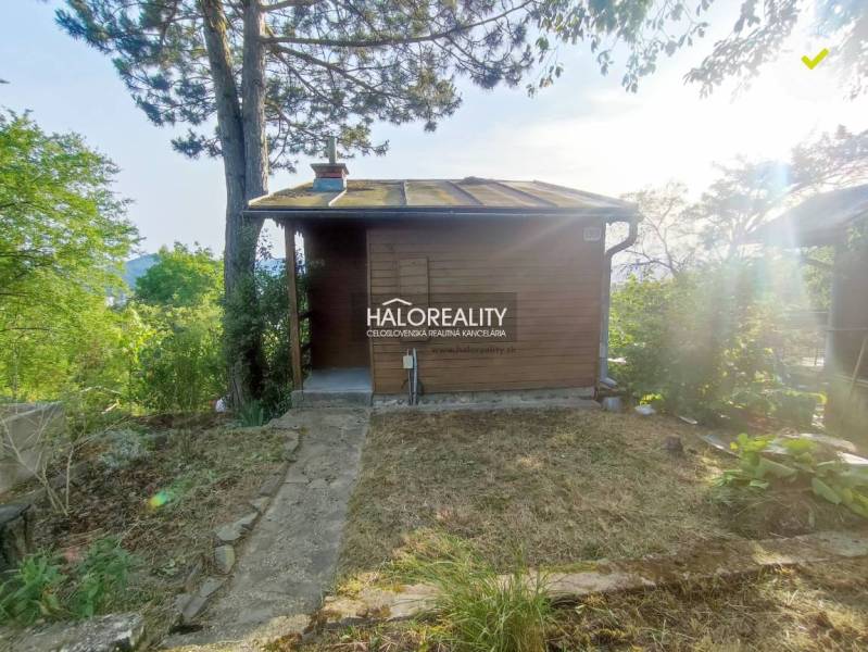 Eine Holzhütte in den Gärten von Zvolen, umgeben von Bäumen und Natur.