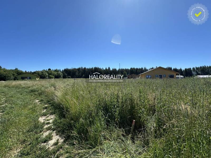 Grundstück zum Wohnen in Jamník mit Rasenfläche und Gebäuden im Hintergrund.