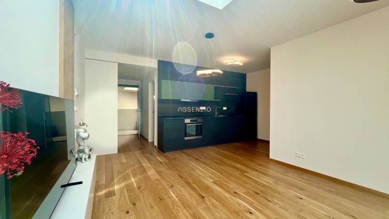 Küche einer 2-Zimmer-Wohnung mit dunkler Küchenzeile und Holzboden, ergänzt durch Beleuchtung.