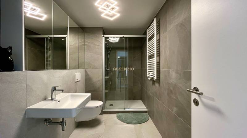 Badezimmer mit Dusche, Waschbecken und Spiegel in einer 2-Zimmer-Wohnung.