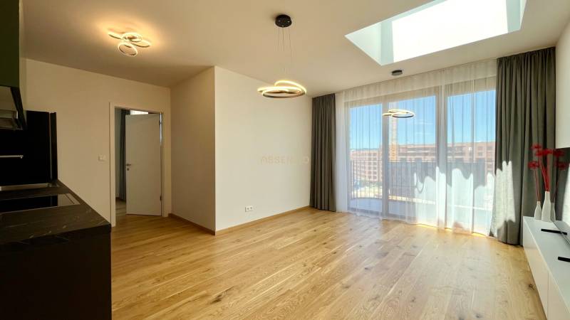 Heller Wohnbereich mit Vorhängen, Holzboden und Küchenzeile in einer 2-Zimmer-Wohnung.