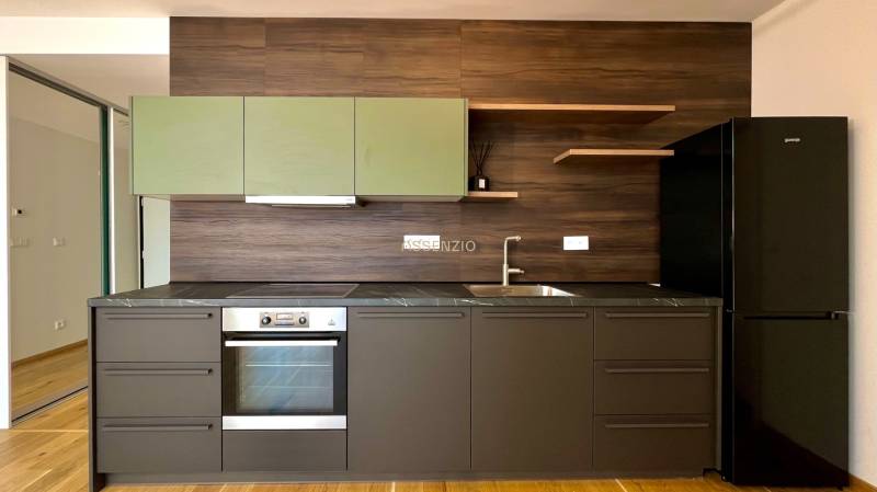 Küche in einer 2-Zimmer-Wohnung mit dunklen Möbeln und eingebautem Gerät.