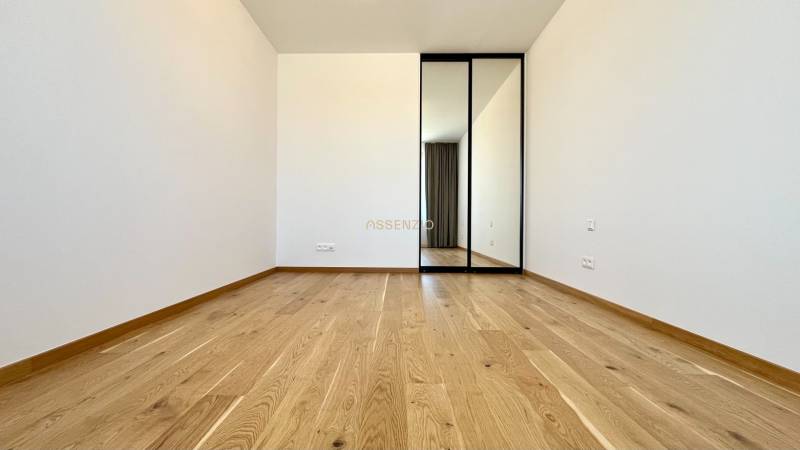 Ein Zimmer mit Holzboden und einem Spiegelschrank in einer 2-Zimmer-Wohnung.