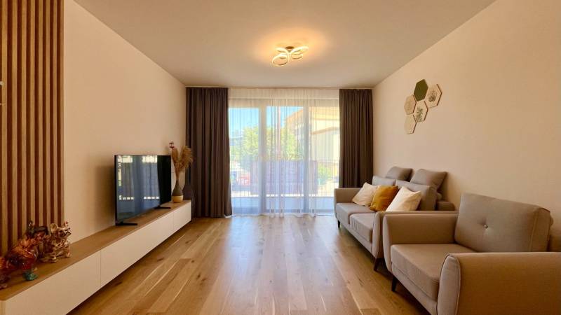 2-Zimmer-Wohnung mit Sofa, Fernseher und Holzboden, leuchtender Kronleuchter.