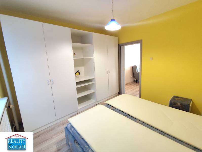 Gelbes Schlafzimmer mit großem weißen Schrank in einer 3-Zimmer-Wohnung.