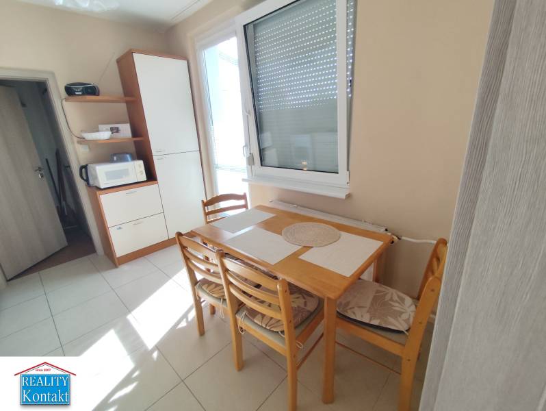 Esstisch mit Stühlen in der Küche einer 3-Zimmer-Wohnung, neben einem Küchenschrank.