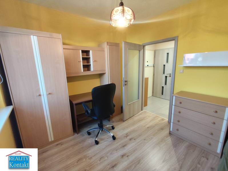 Ein Zimmer mit Möbeln in einer 3-Zimmer-Wohnung, Holzboden, gelbe Wände, Schreibtisch, Stuhl.