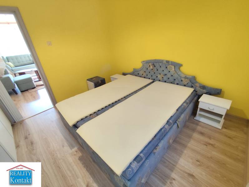 Schlafzimmer in einer 3-Zimmer-Wohnung mit gelber Wand, Bett und Nachttischen.