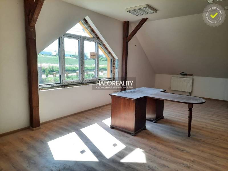 Dachzimmer mit Holztisch und großem Fenster in einer 2-Zimmer-Wohnung.