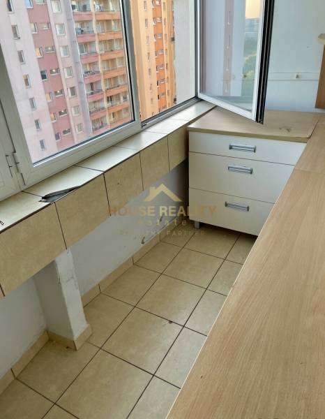 Loggia in einem Einzimmerapartment mit Blick auf die benachbarten Plattenbauten durch ein großes Fenster.