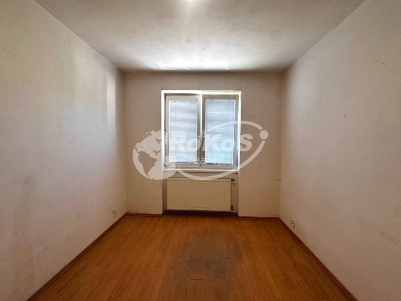 Ein leerer Raum mit Parkettboden und einem Fenster in einer 3-Zimmer-Wohnung.