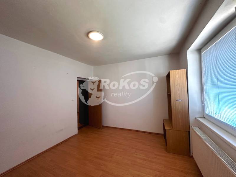 Ein leerer Raum in einer 3-Zimmer-Wohnung mit hellen Möbeln und einem großen Fenster.