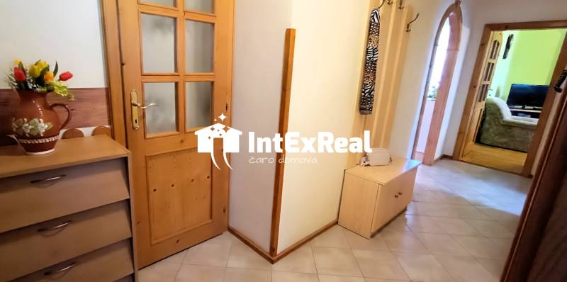 Der Flur in der 3-Zimmer-Wohnung mit Holzmöbeln und Dekoration in der Vase.