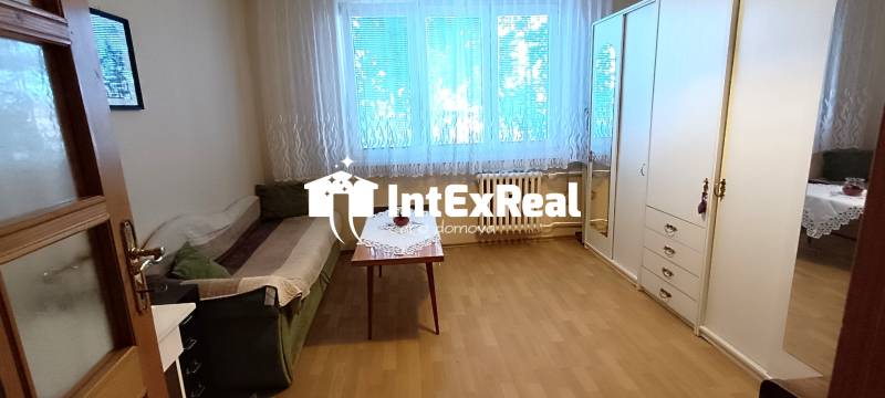 Ein Zimmer in einer 3-Zimmer-Wohnung mit einem Sofa, einem Tisch und einem großen Schrank.