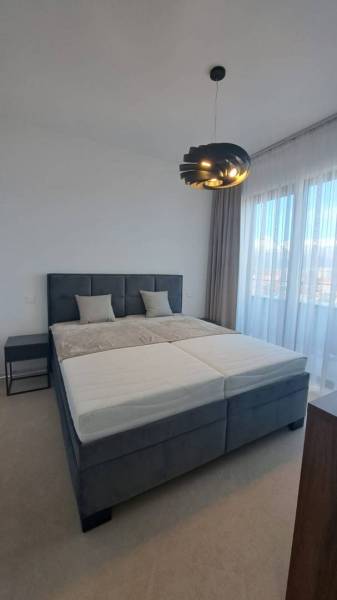 Schlafzimmer mit großem Bett und moderner Lampe in einer 2-Zimmer-Wohnung.