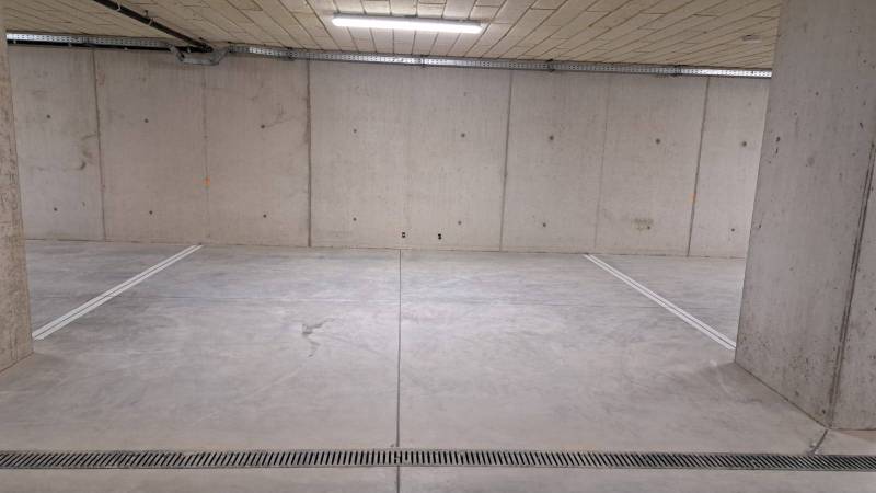 Parkplatz in einer Tiefgarage mit Betonwänden und -boden.