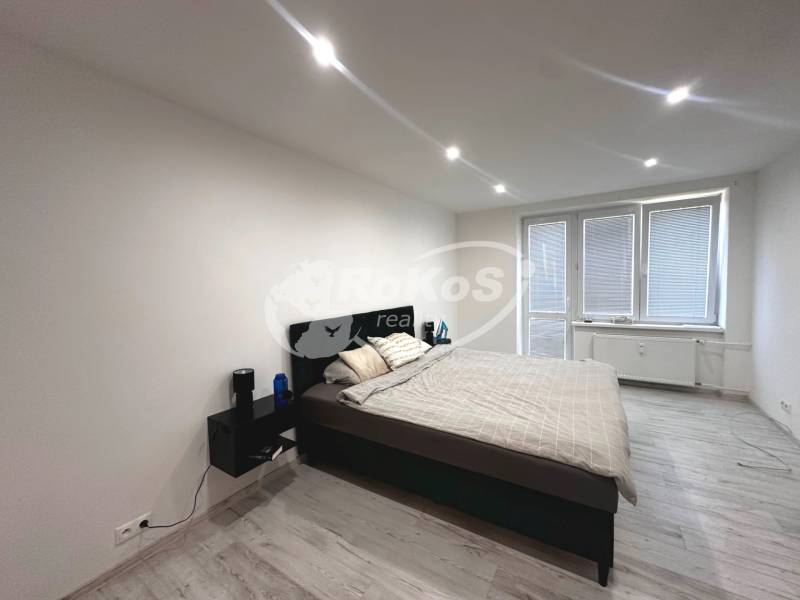 Schlafzimmer in einer 2-Zimmer-Wohnung, mit Bett und Nachttischen, hellem Boden.