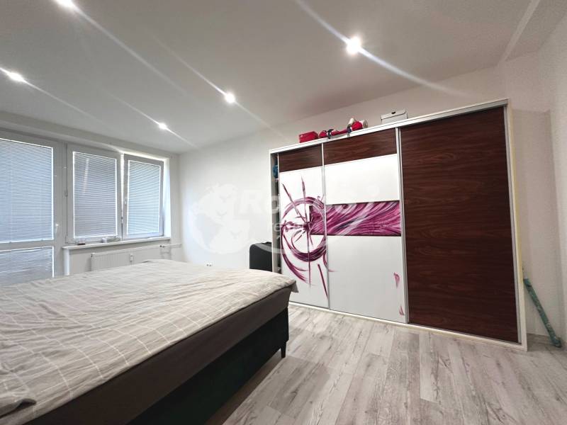 Schlafzimmer mit Bett, Einbauschrank und Fenstern in einer 2-Zimmer-Wohnung.