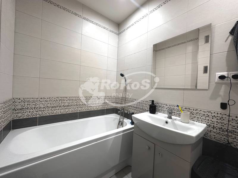 Badezimmer in einer 2-Zimmer-Wohnung mit Badewanne, Waschbecken und Spiegel an der Wand.